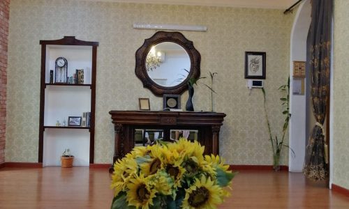 A living room with a vase of sunflowers and a chandelier.