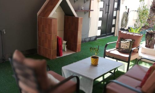 A patio with furniture and a dog house.