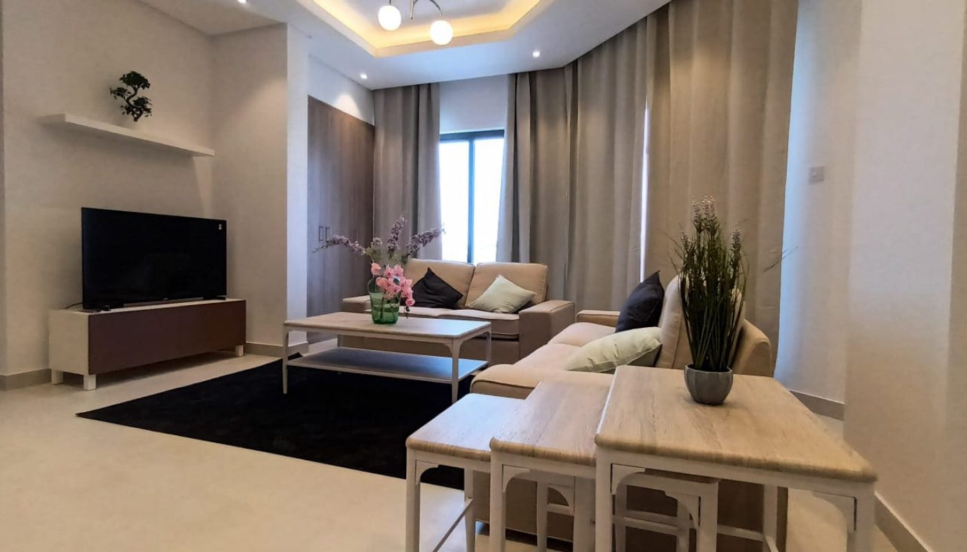 A brand new living room with a flat screen tv and a coffee table in a 3BR apartment for rent in Al Janabiyah.