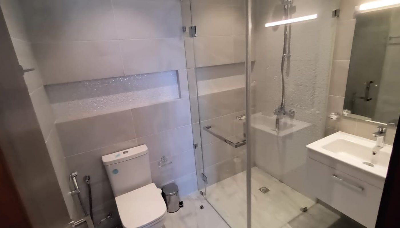 Brand new apartment with glass shower stall and toilet.