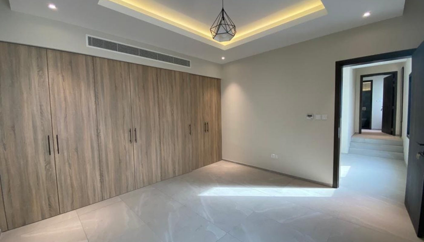 A brand new villa for rent in Saar with wooden cabinets and a ceiling light.