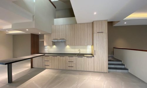 A modern kitchen with wooden cabinets and brand new counter tops.