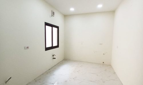 Modern, empty room with white walls and a window.