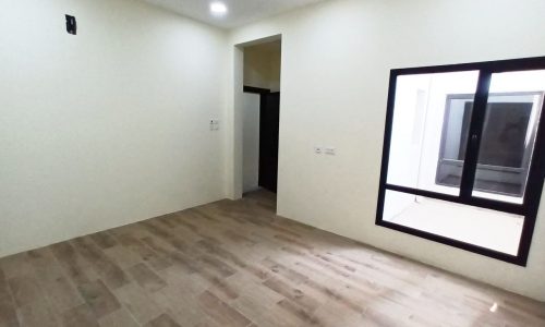 An empty modern room with wooden floors and a window.