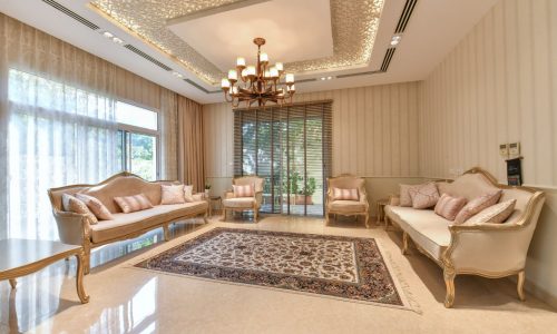 A luxurious living room with beige furniture and a chandelier.