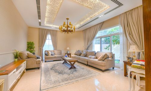 A luxurious living room with beige furniture and a chandelier in a Villa.