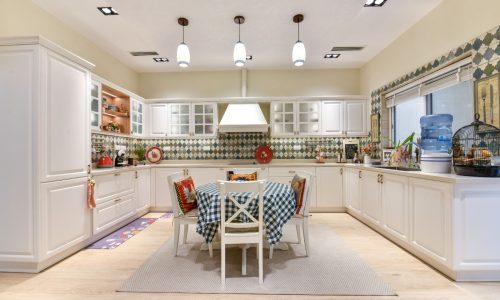 A white kitchen with a table and chairs in an elegant villa for sale.