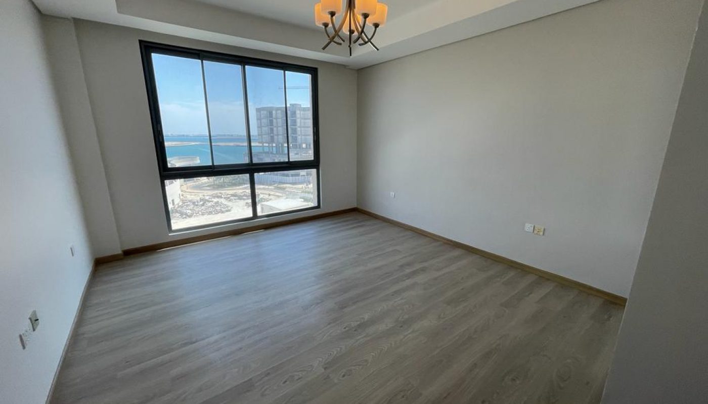 An empty apartment with hardwood floors and a view of the ocean available for rent.