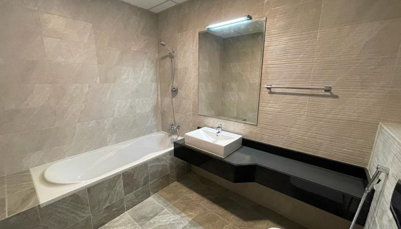 An apartment bathroom with a toilet, sink, and mirror available for rent in Durrat Marina.