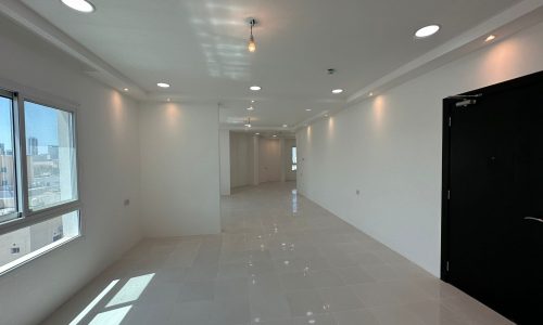 A freshly painted hallway in a commercial office space, adorned with pristine white walls and featuring a sleek black door.