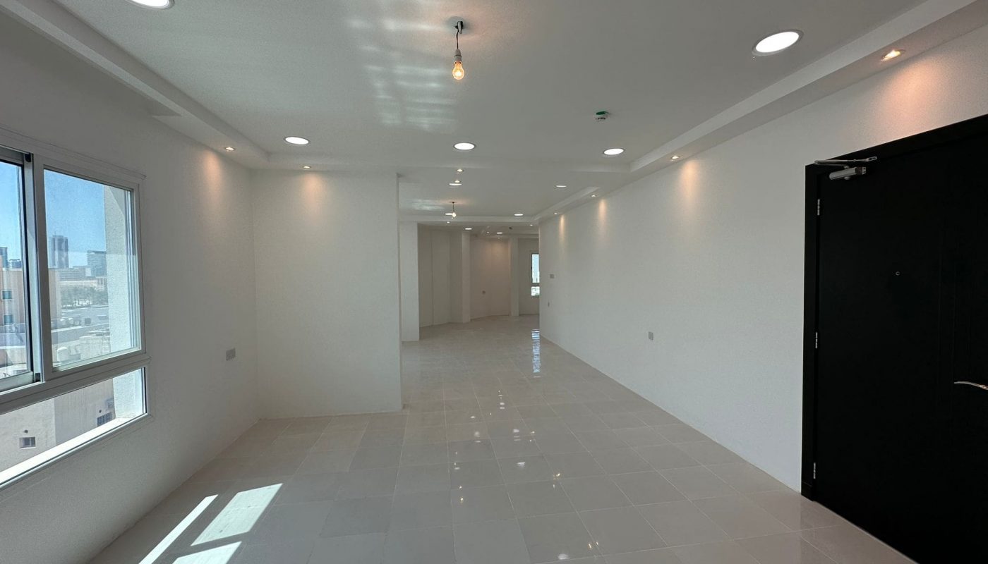 A freshly painted hallway in a commercial office space, adorned with pristine white walls and featuring a sleek black door.