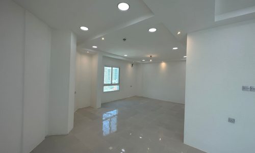 An empty room with white walls and light fixtures available for rent in Sanabis. This commercial office space is ready for occupancy.