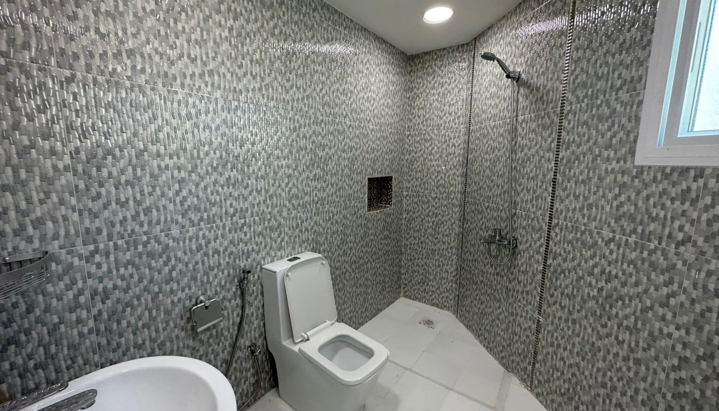 A commercial office with tiled walls and a toilet available for rent in Sanabis.