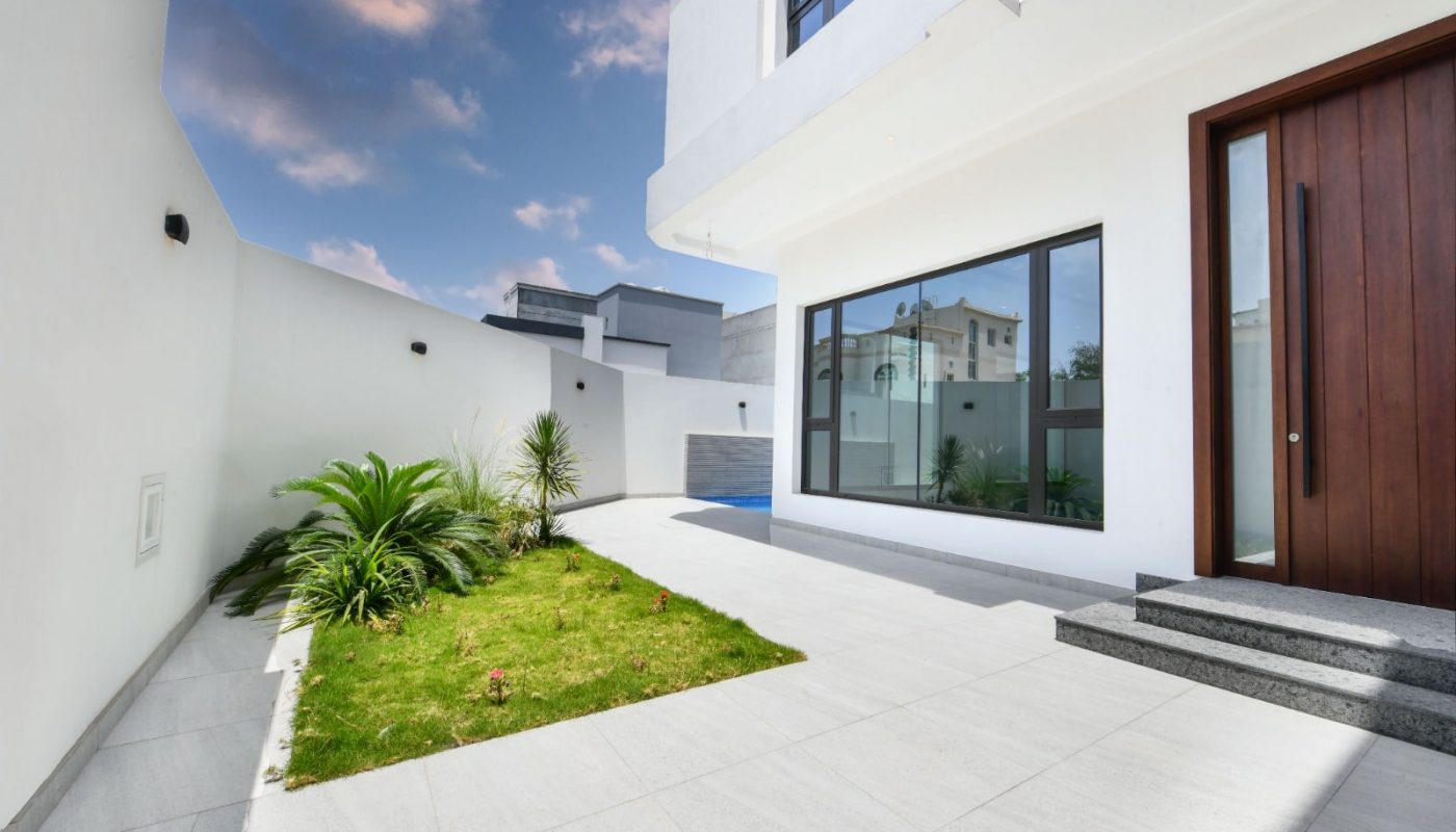 Modern Villa for Sale in Janabiyah features a white door and a green lawn.