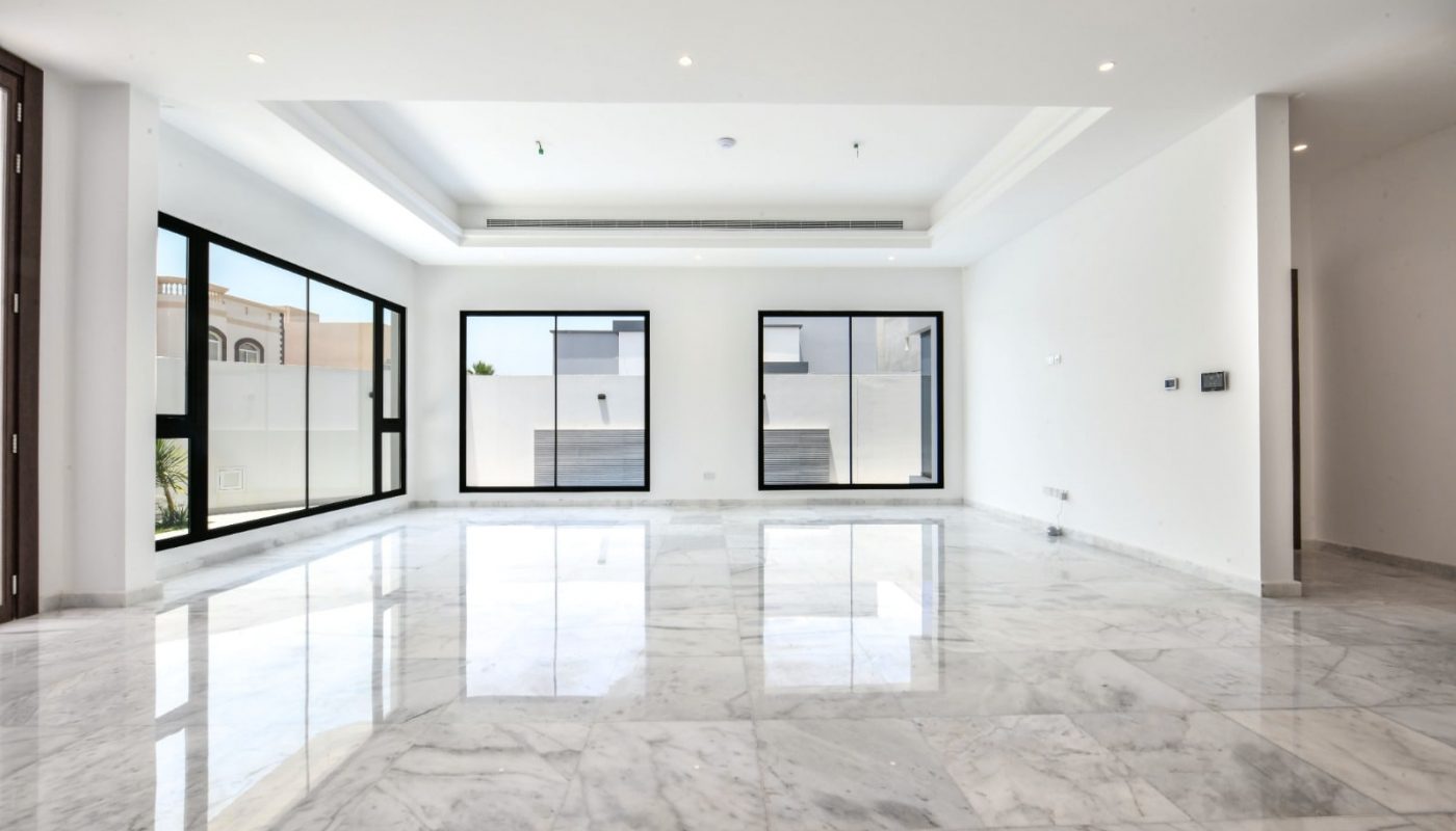 A large empty room with marble floors and large windows in a modern villa for sale.