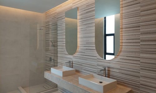 A modern bathroom with two sinks and a shower, located in a luxury villa in Saar, available for sale.