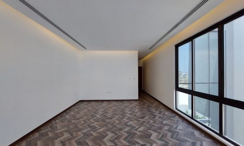 A spacious room with wooden floors, adorned by a large window that fills the space with natural light.