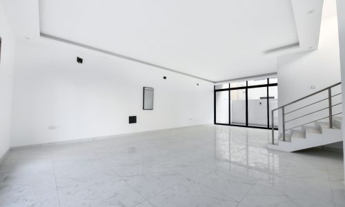 An empty room with white walls and marble floors in a luxury villa for sale.