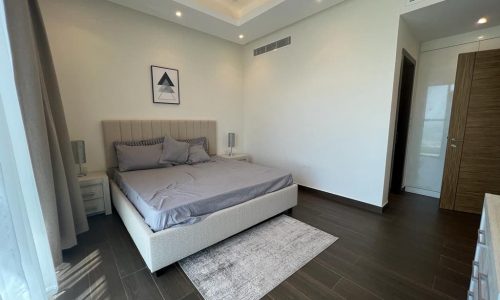 An Amazing Apartment in Juffair with a bed and wooden floors.