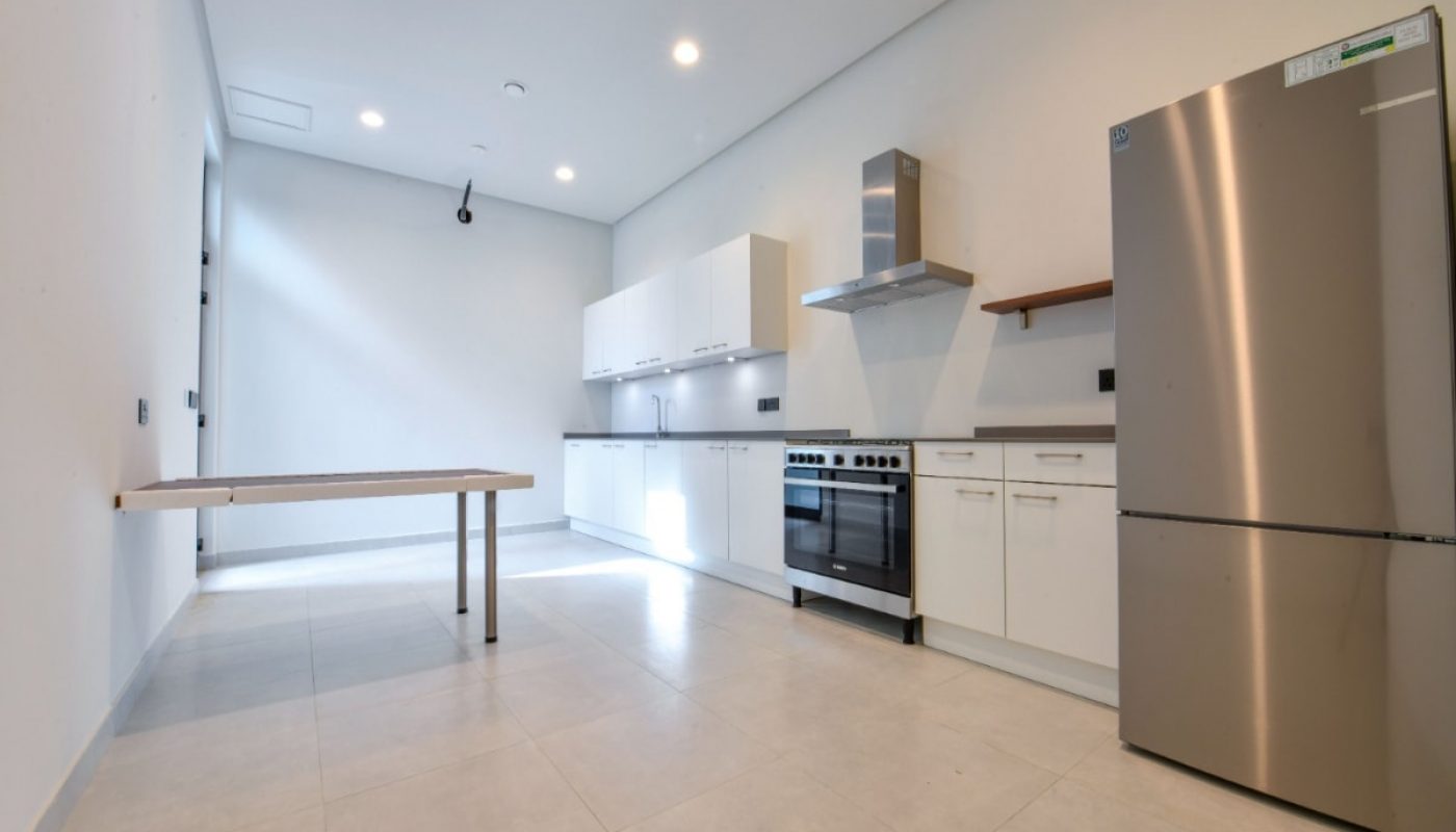 A luxurious villa for sale in Saar with a kitchen featuring stainless steel appliances and white walls.