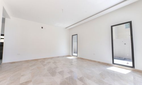 A spacious villa with white tile floors and sliding glass doors.