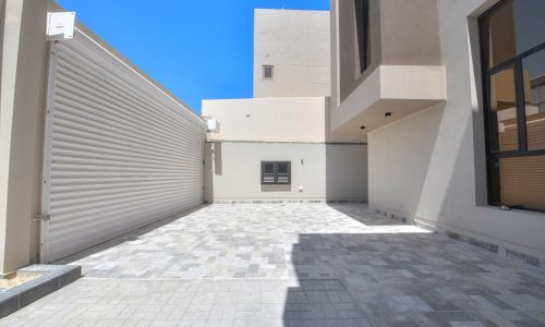 A picturesque courtyard with a garage and a charming building in the background, available for sale in Damistan.