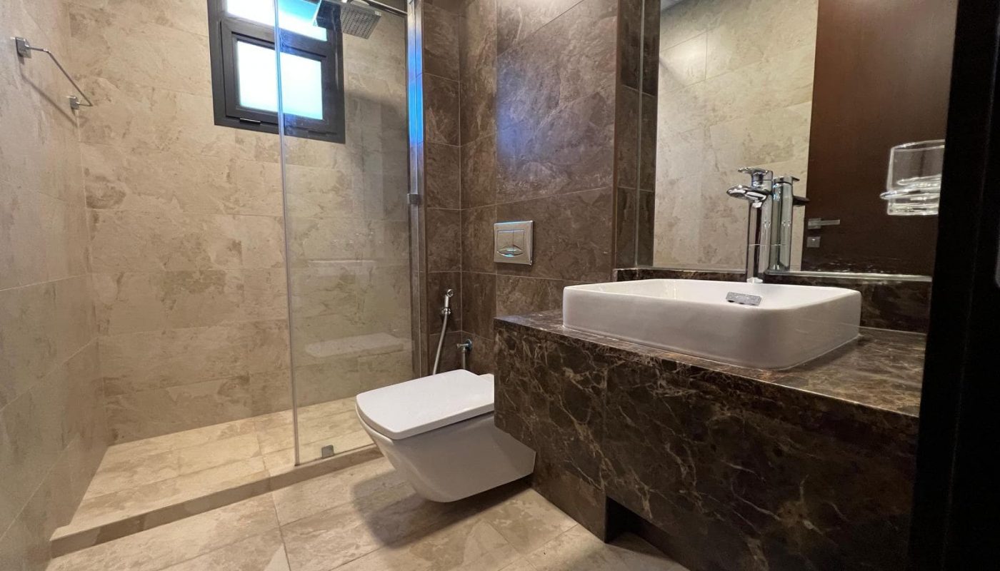 A bathroom with a toilet, sink and shower.