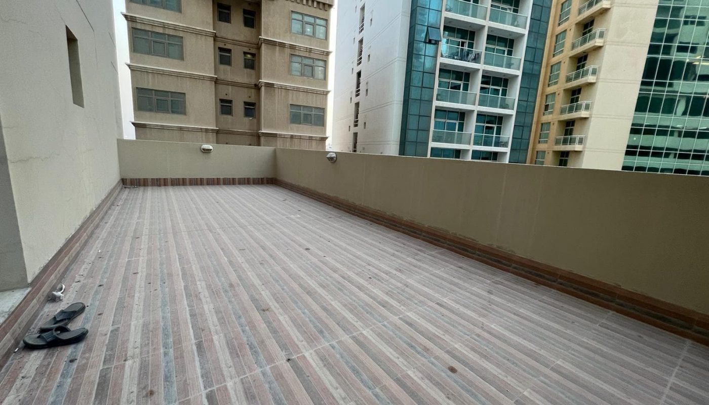 A spacious balcony with a wooden floor in an apartment building.