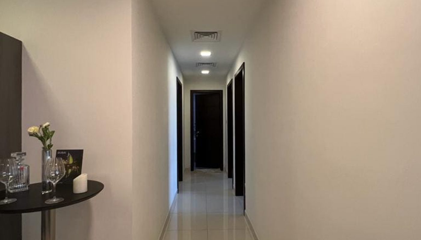 A luxury apartment hallway with a white tile floor and a small table.