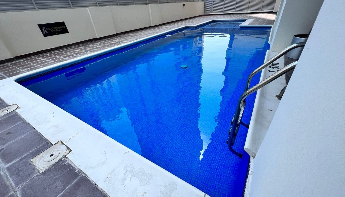 A modern and luxurious apartment building with a swimming pool in the middle of a bustling city.