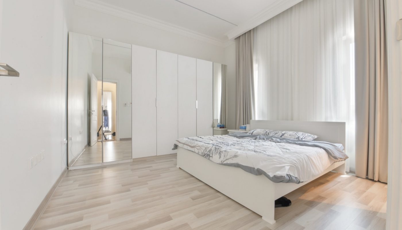 A modern villa bedroom in Janabiyah available for rent, featuring stunning wooden floors and a comfortable bed.