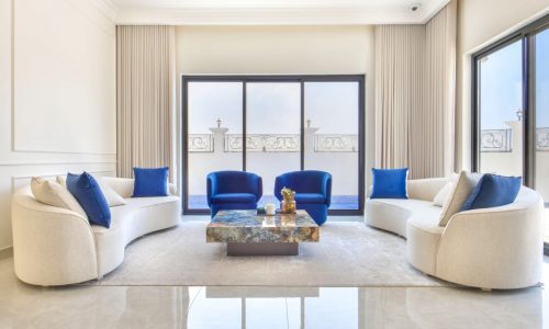 A modern villa living room in Janabiyah available for rent, featuring white furniture with elegant blue accents.