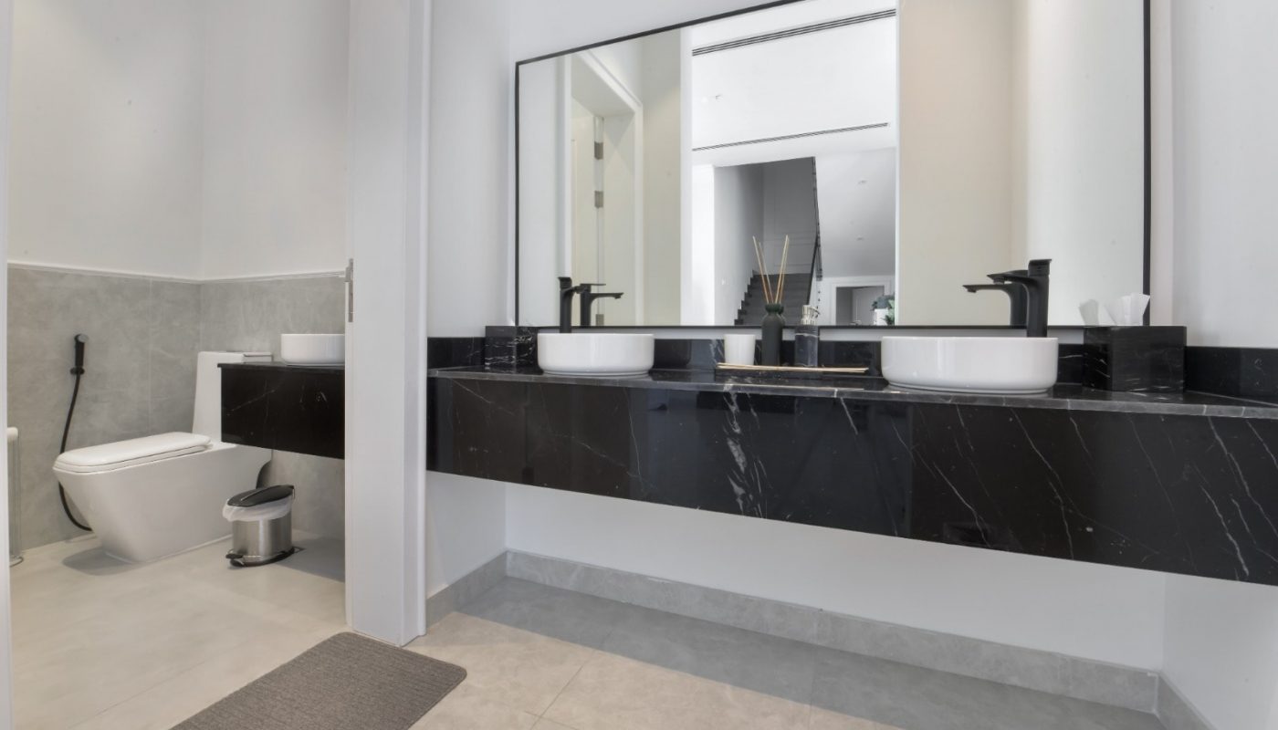 Rent a modern villa in Janabiyah with a stylish bathroom featuring black marble countertops.