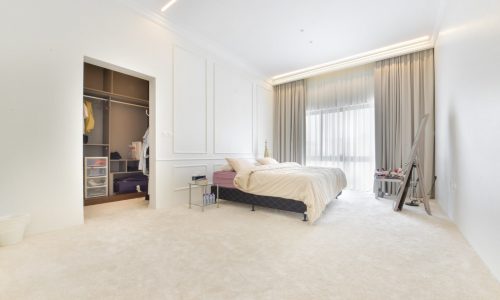 A modern white bedroom in a villa, complete with a bed and closet.