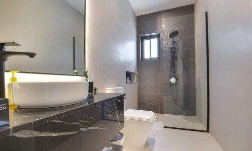 A modern bathroom with a sink, toilet and shower in a Janabiyah modern villa available for rent.