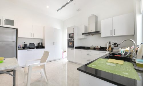 A modern villa with a kitchen featuring white cabinets and black countertops.