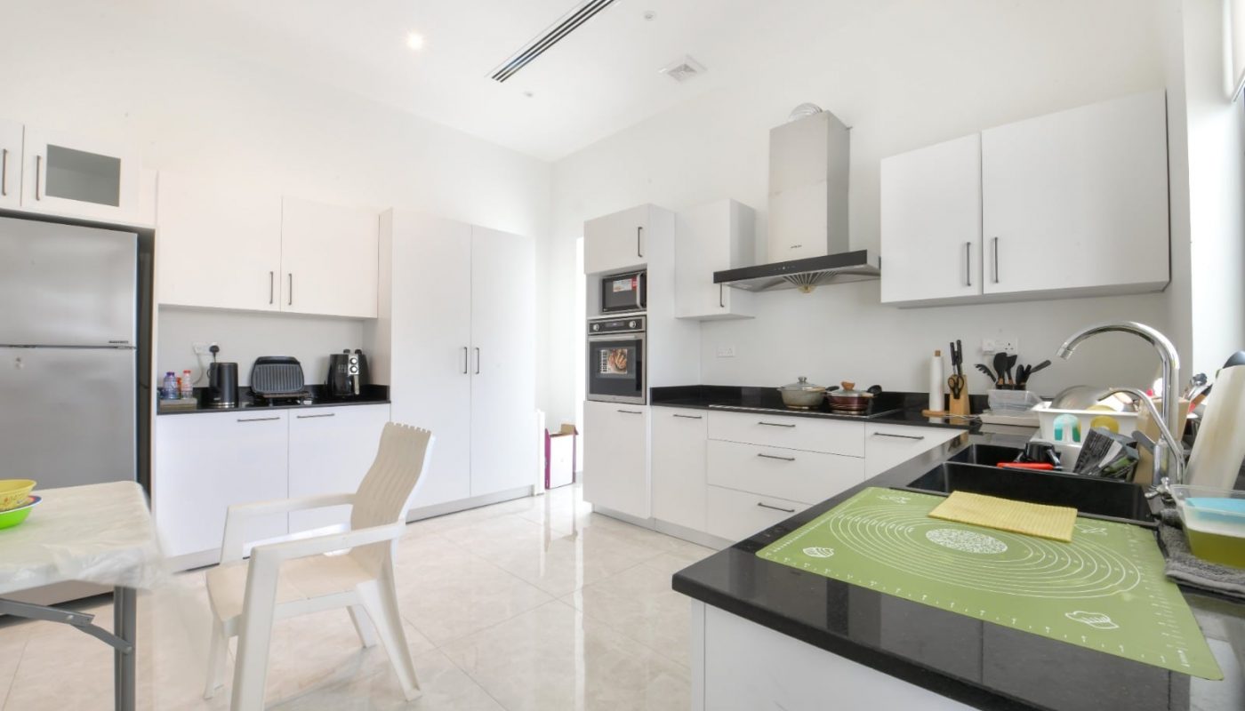 A modern villa with a kitchen featuring white cabinets and black countertops.
