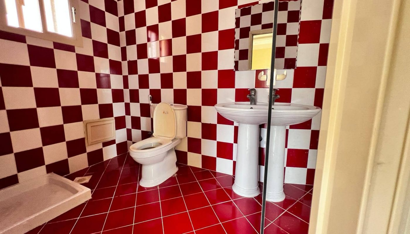 A spacious apartment bathroom with a red and white checkered floor available for rent.