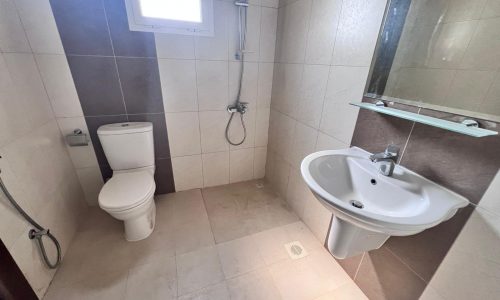 A spacious bathroom with a toilet, sink and shower.