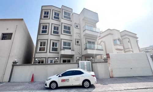 A spacious apartment building in Juffair with a car parked in front.