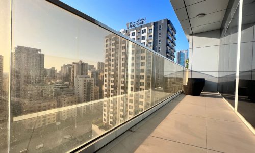 A luxury living experience with a balcony featuring glass railing, offering breathtaking views of the city.