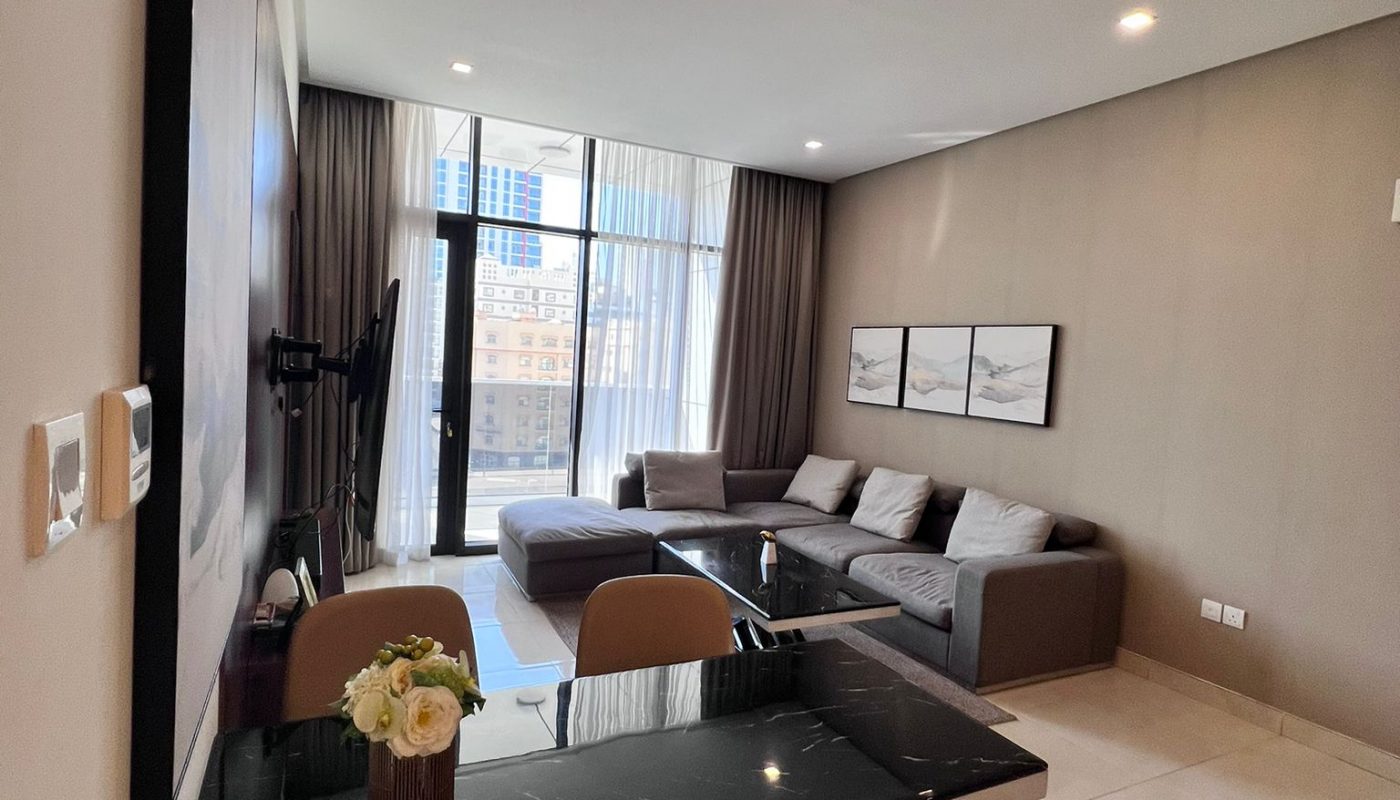 Modern living and dining area with a black dining table, beige chairs, gray sectional sofa, large windows, and city view outside.