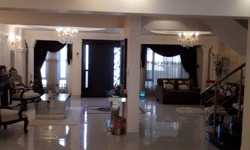 A luxurious living room in a 3BR Villa with a chandelier and marble floors located in Tubli.