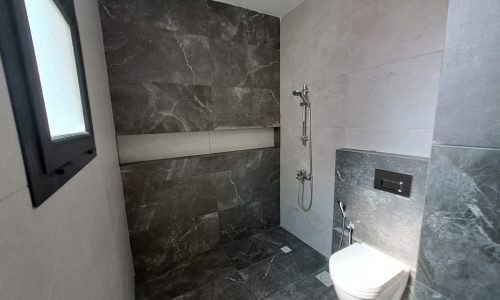 A modern bathroom with a sophisticated design, featuring a toilet and shower.