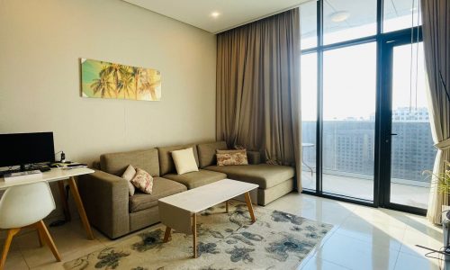 A modern living room with a flat screen TV and a balcony in a luxury apartment.