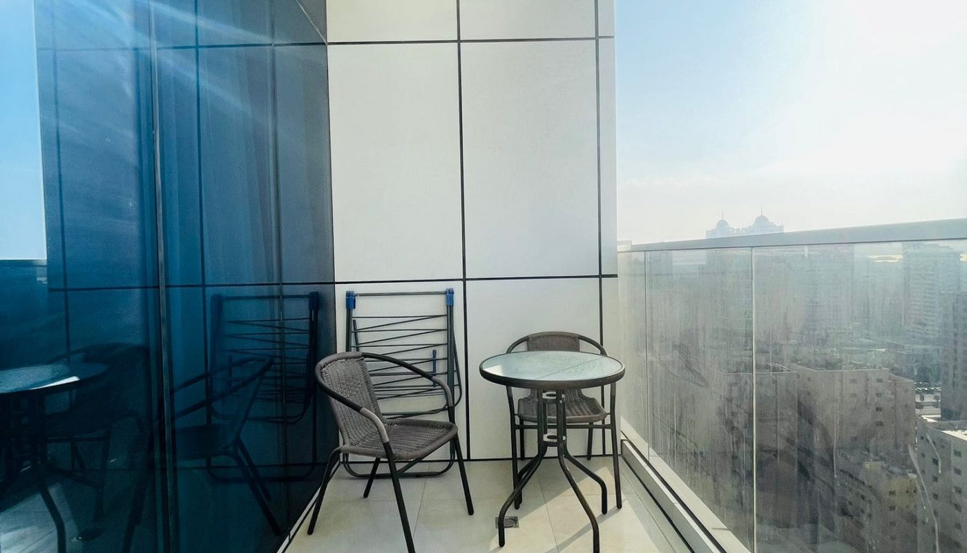 A modern balcony with a table and chairs overlooking a city.