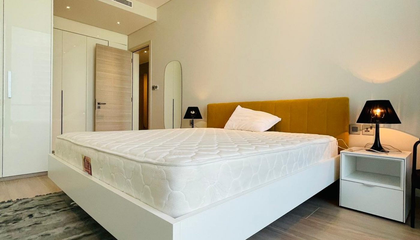 A bedroom with a white bed and a yellow rug.