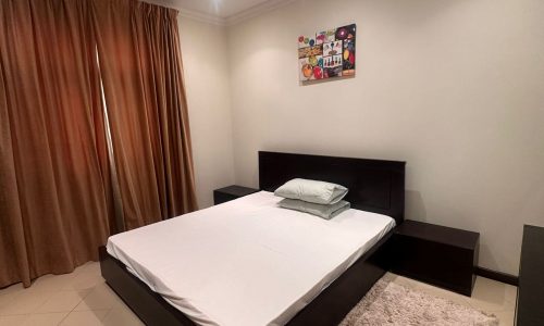 A modern bedroom with a bed and a dresser in a luxury apartment.