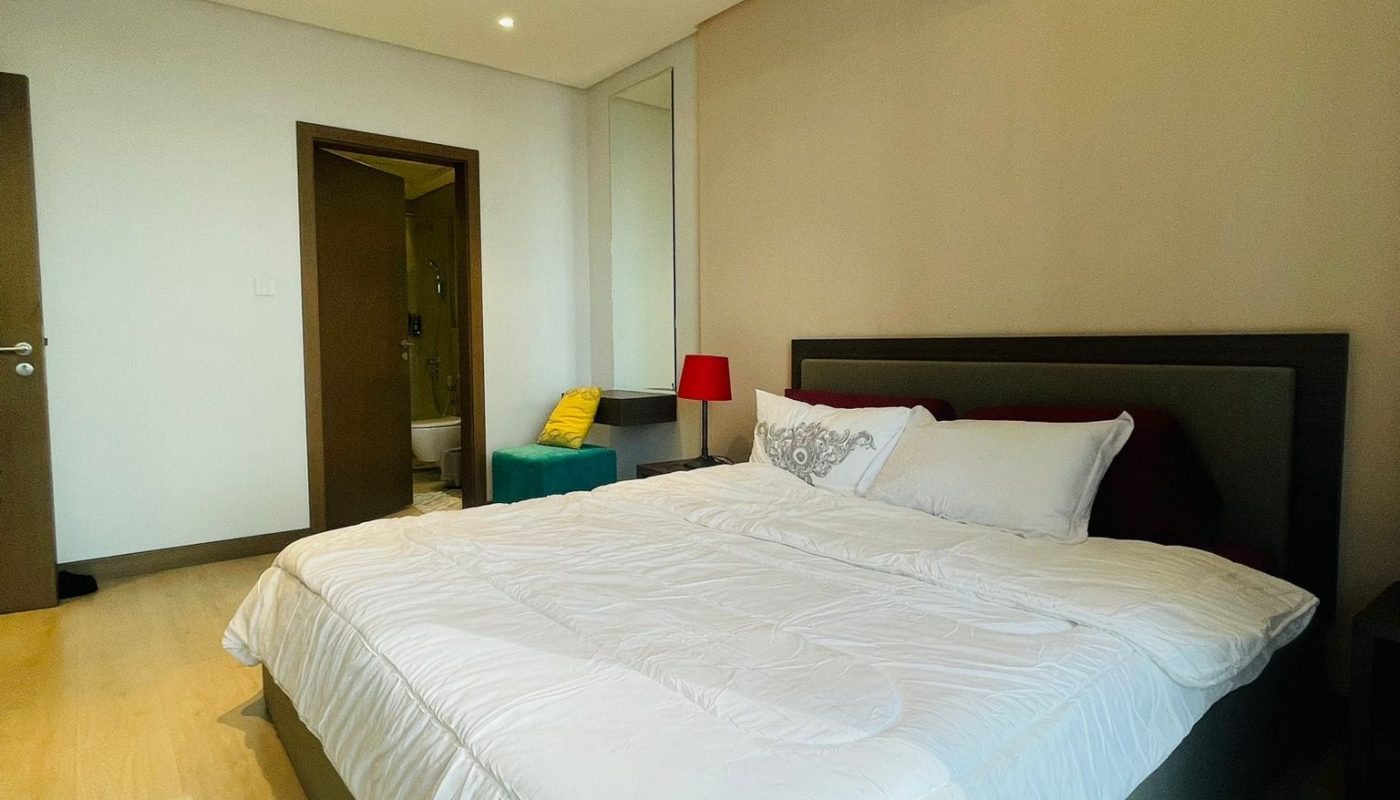 A luxury 1 BR apartment in Seef with exceptional amenities. This stunning bedroom features a white bed and elegant wooden floors.