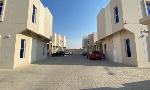 A row of buildings with cars parked in front of them.